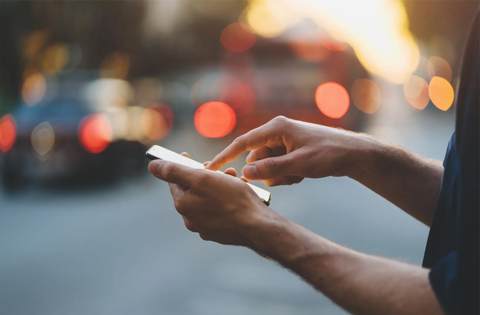 A person scrolling on a smartphone outdoors