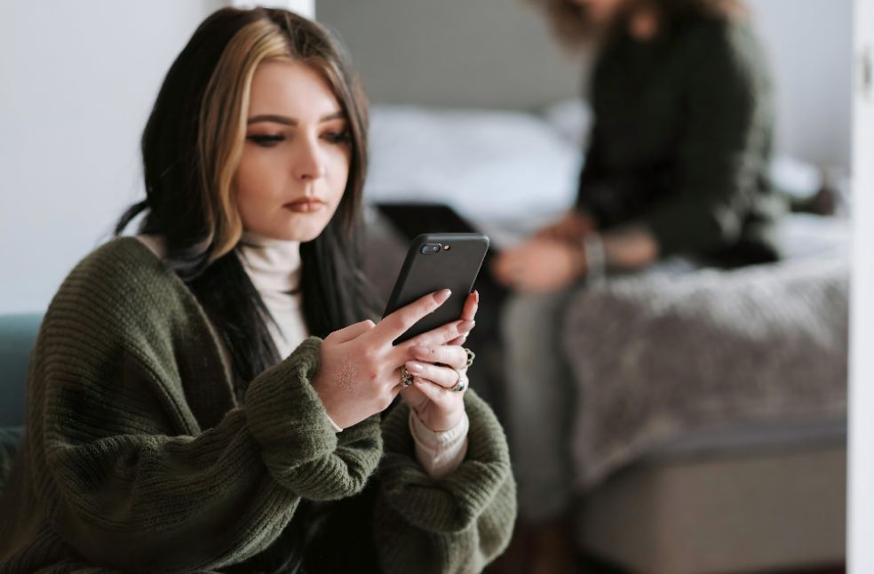 Thoughtful young woman messaging on smartphone