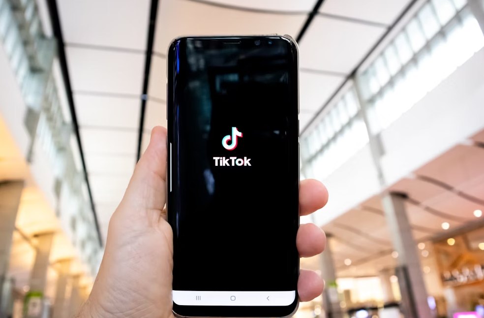 Man holding mobile phone opening Tik Tok application