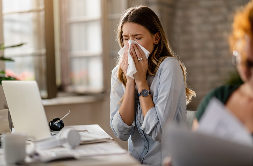 Young women sneezing on to a tissue
