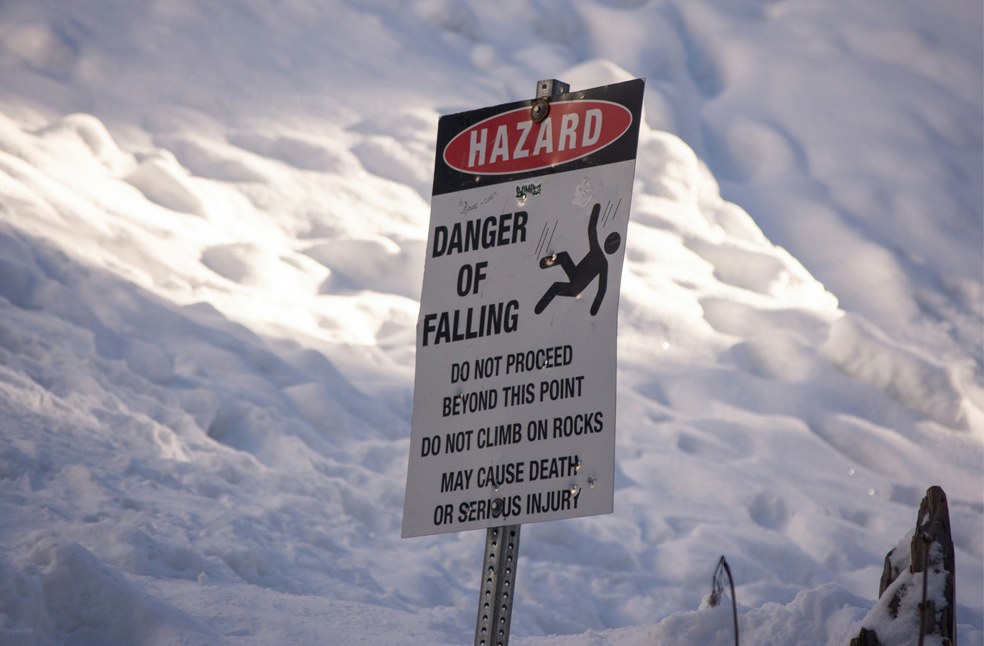 Hazard sign board below the snow mountains