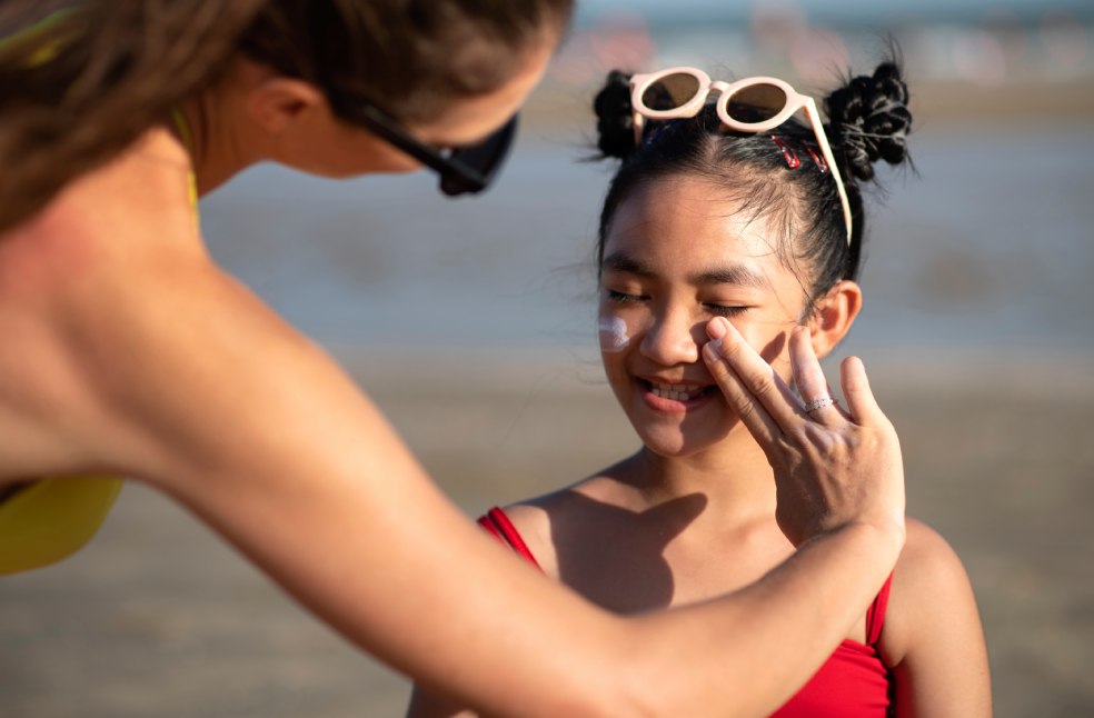 Women applying sunscreen on girl