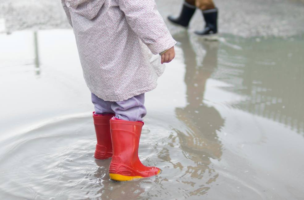 Child wearing boots and sitting in the water