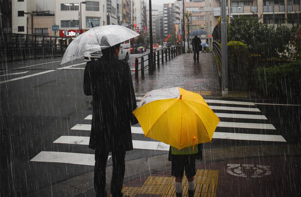 Family crossing the road on a rainy day