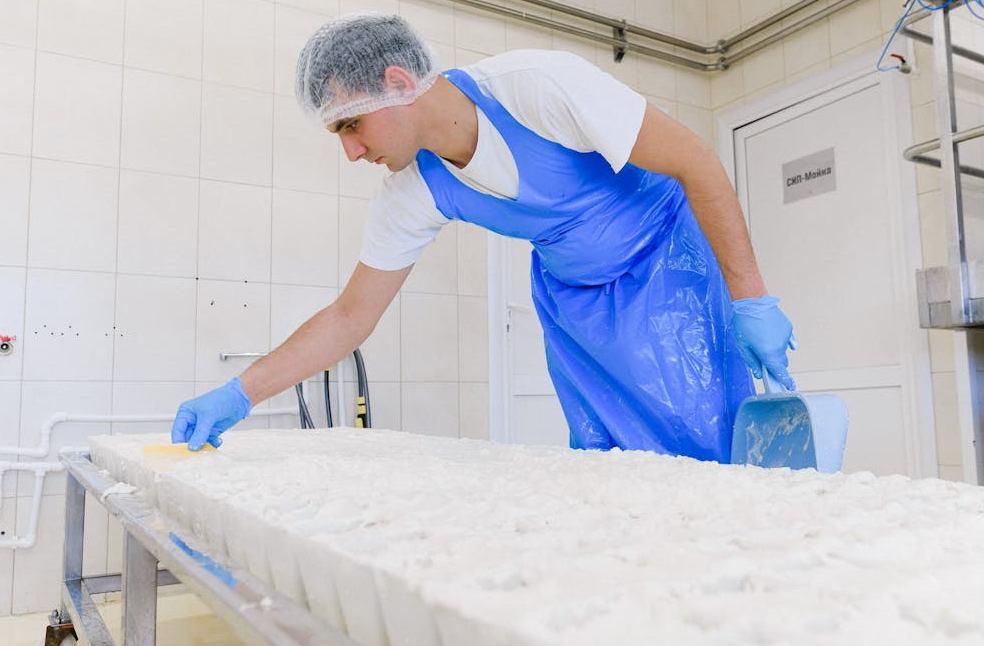 Man working inside a dairy facility while preparing feta cheese products