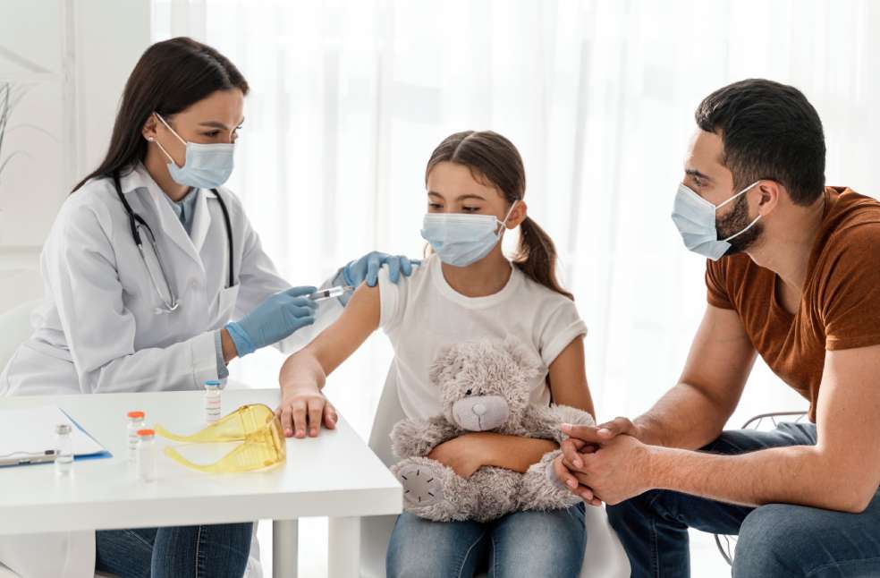 Girl being vaccinating next to her father