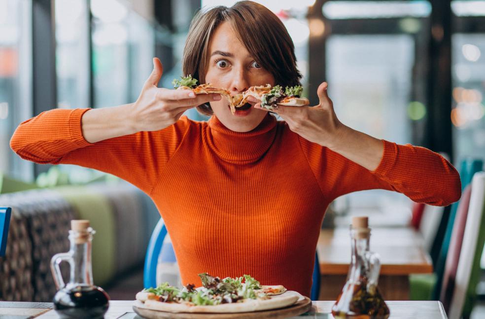 Young-pretty-woman-eating-pizza-at-pizza-bar