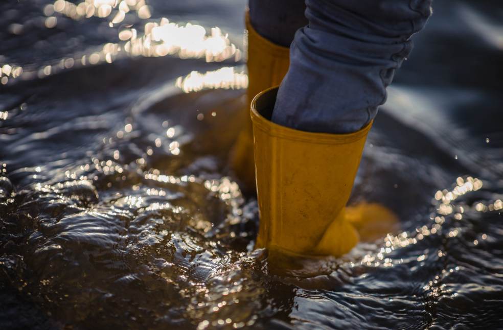person in blue denim jeans and yellow boots standing on water