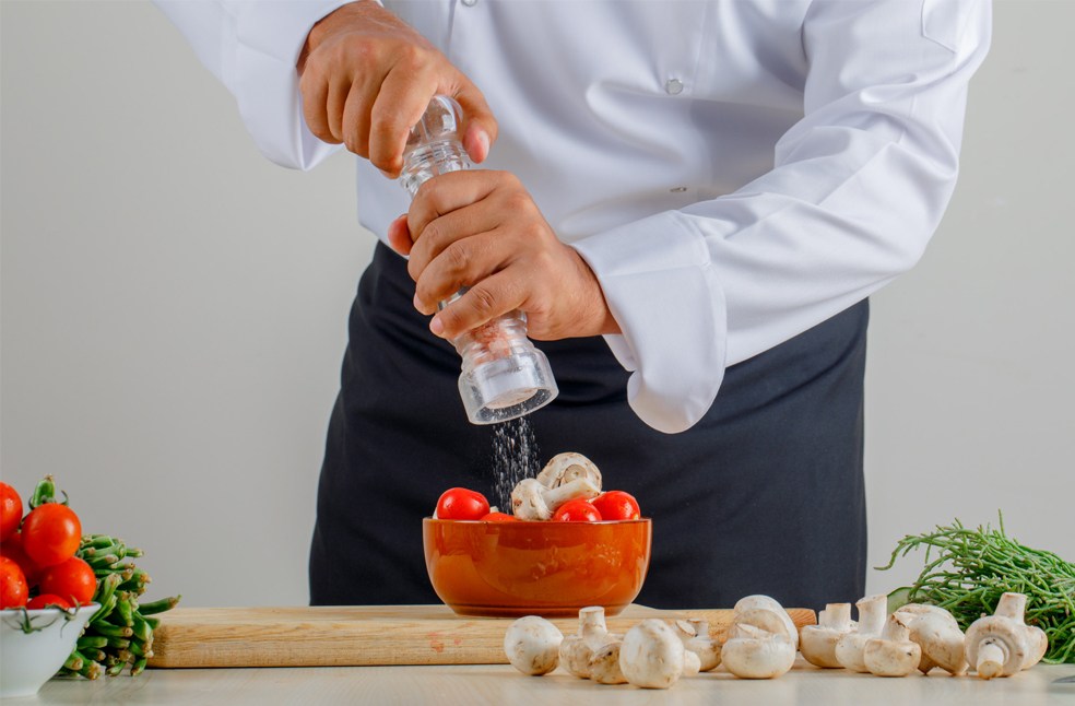Chef adding salt to food in the kitchen