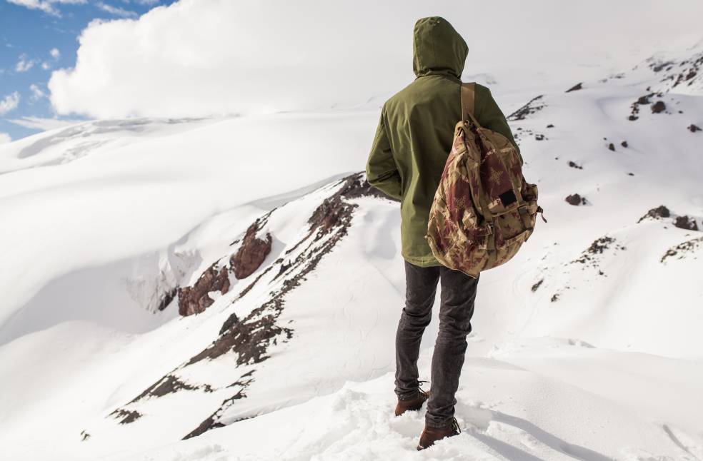 young hipster man hiking in mountains, winter vacation traveling