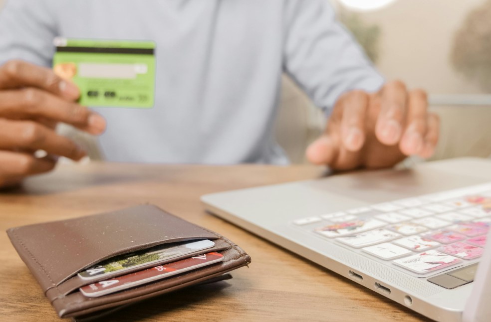 A Person Holding a Bank Card while Using a Laptop