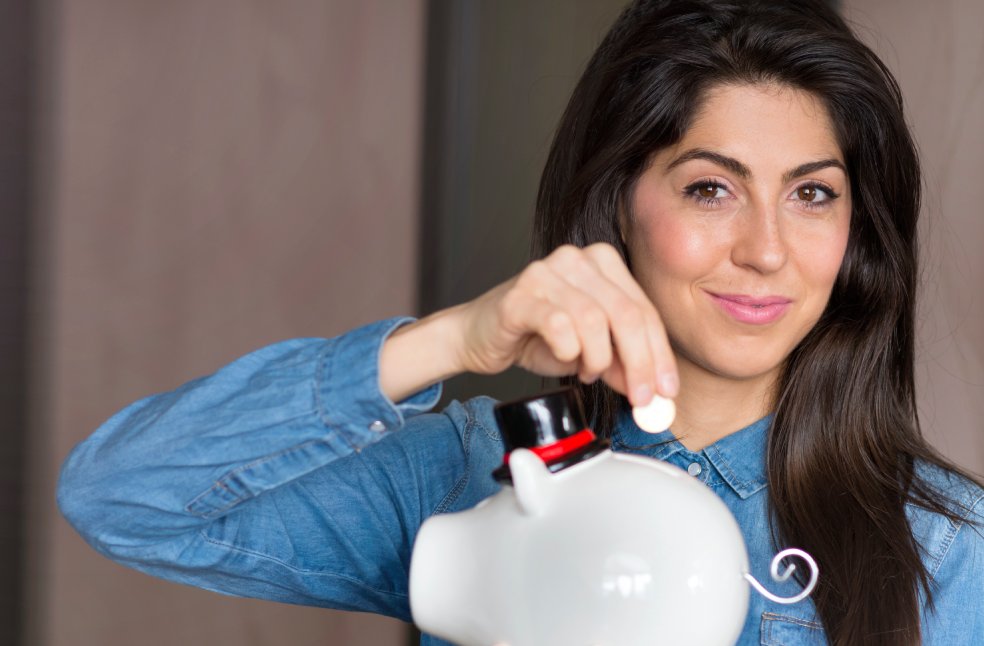 Happy girl posing with her piggy bank