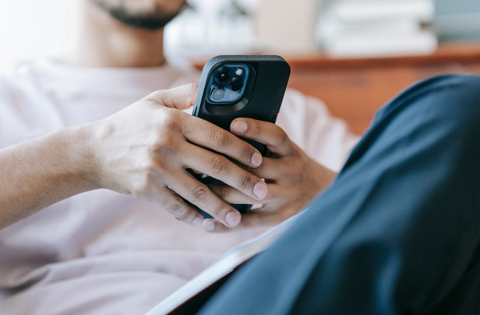 Crop bearded man using smartphone in living room
