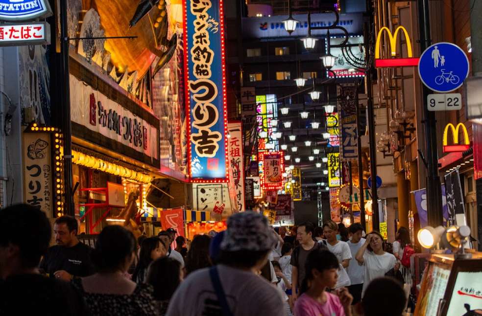 A Busy Street between Illuminated Buildings in a City at Night in Japan