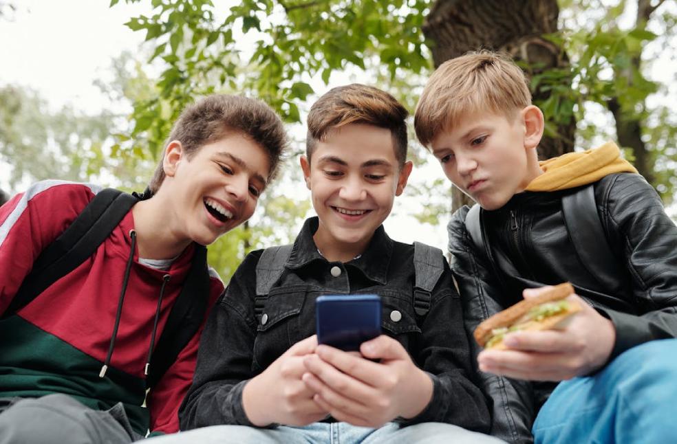 Three boys using a smartphone amid social media ban