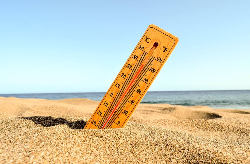 A closeup shot of a thermometer in the beach sand