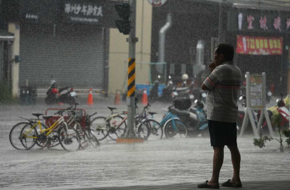 Man Smoking and Watching a Downpour on a City Street