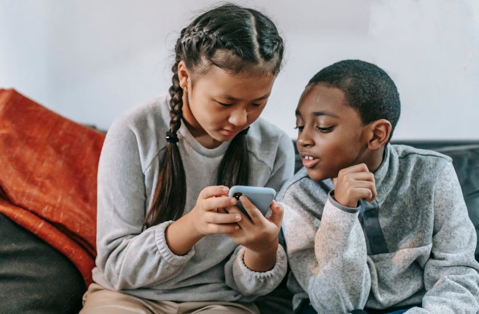 Multiethnic friends watching smartphone on sofa at home