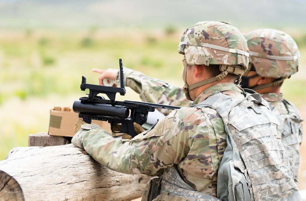 Man in Green and Brown Camouflage Uniform Holding Black Rifle