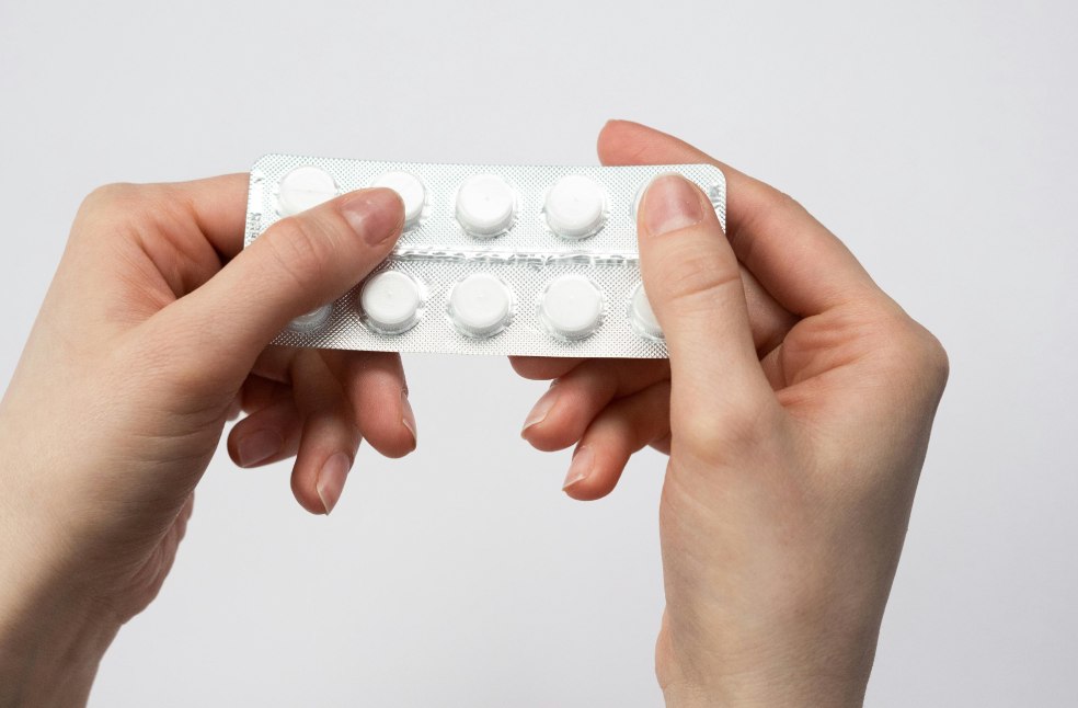 Close-up of hands holding a blister pack of white pills