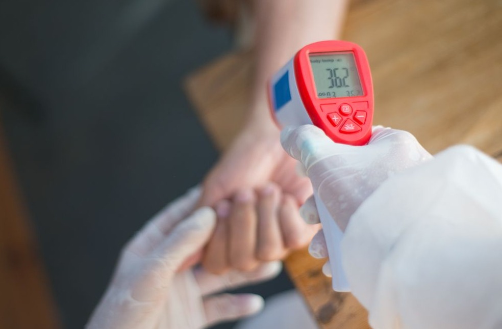 Close-up of a healthcare worker using an infrared thermometer to measure a patient's temperature