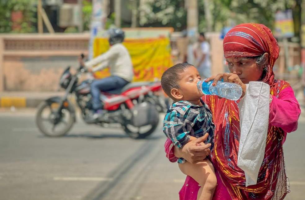 A mother gives water to her child on a hot day
