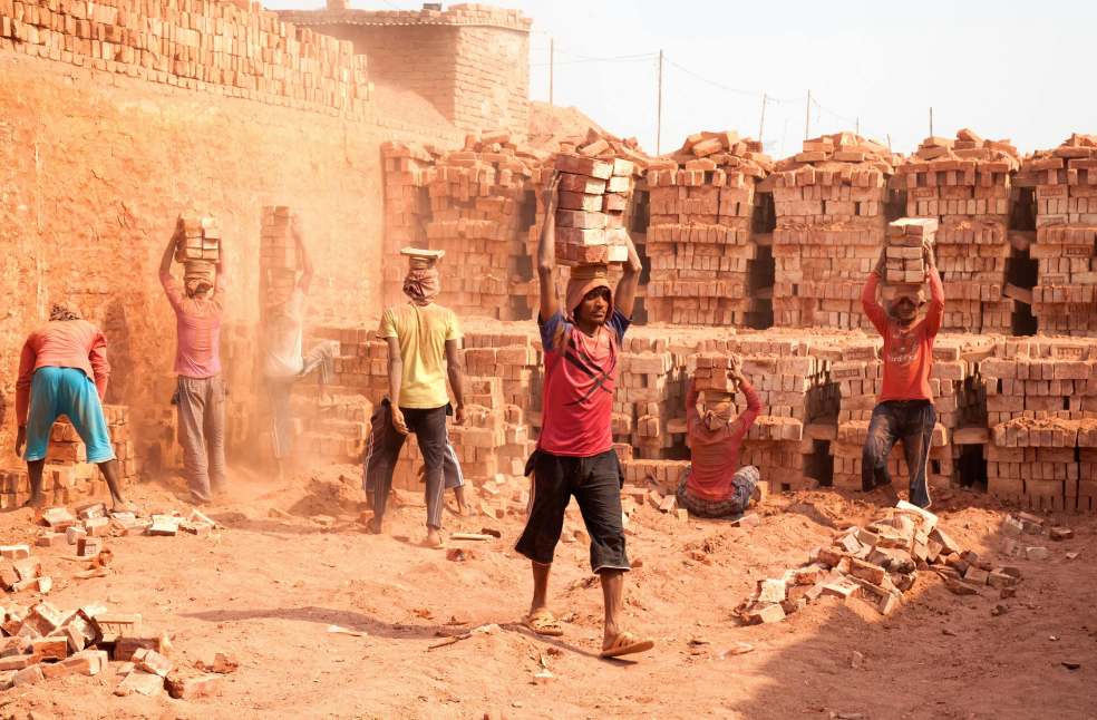 Laborers carrying bricks at outdoor kiln