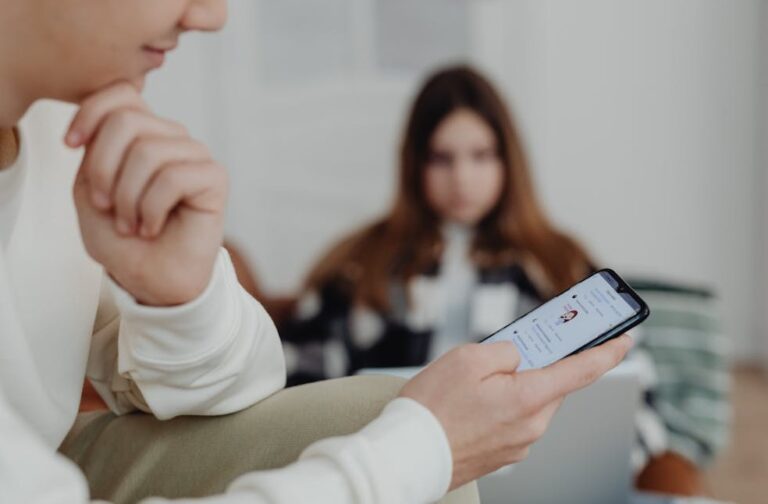 YouTube, TikTok and Snap settle addiction lawsuit Teens using smartphones indoors with a blurred background, suggesting social media engagement