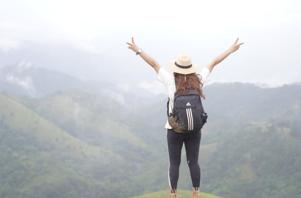 A woman hiker on a mountain top celebrating the scenic view with open arms.