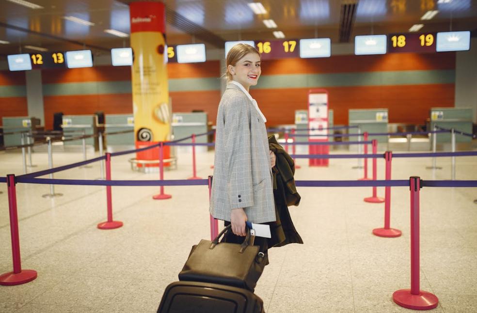 Confident businesswoman with luggage smiling at the airport check-in area