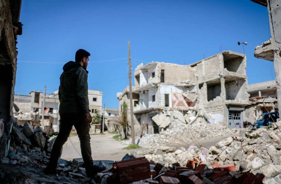 A man walks through the rubble of destroyed buildings