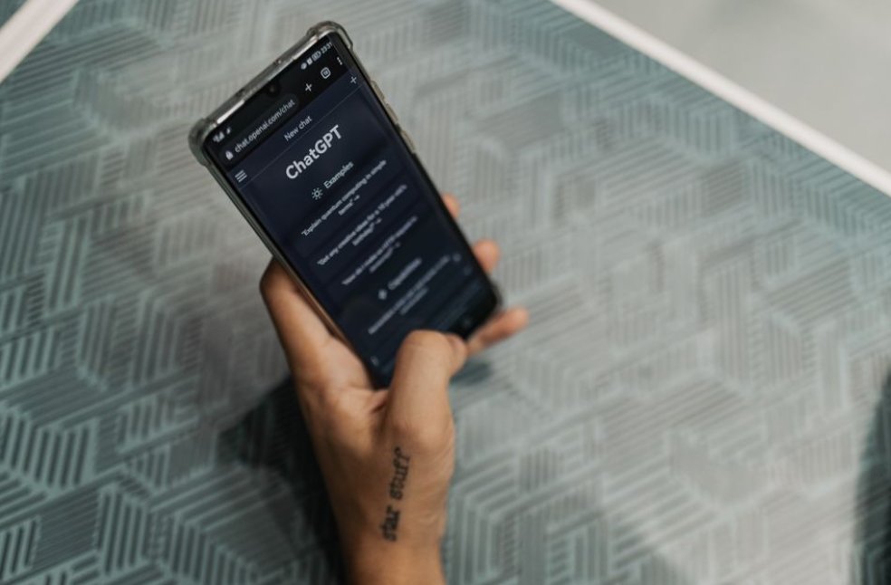 Close-up of a person holding a smartphone displaying the ChatGPT application interface on a patterned table