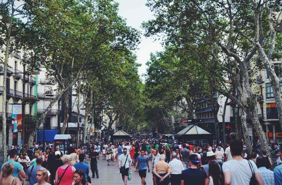 A vibrant street filled with people and trees, showcasing urban life in Barcelona, Spain