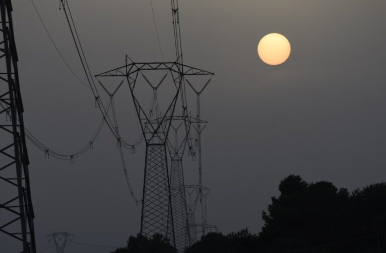Power outages hit France as historic heatwave scorches Europe Transmission towers silhouetted against a setting sun