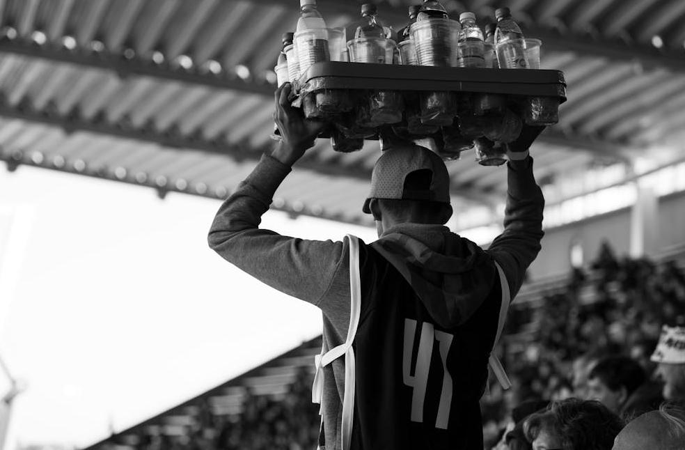 A vendor carrying drinks at a football match