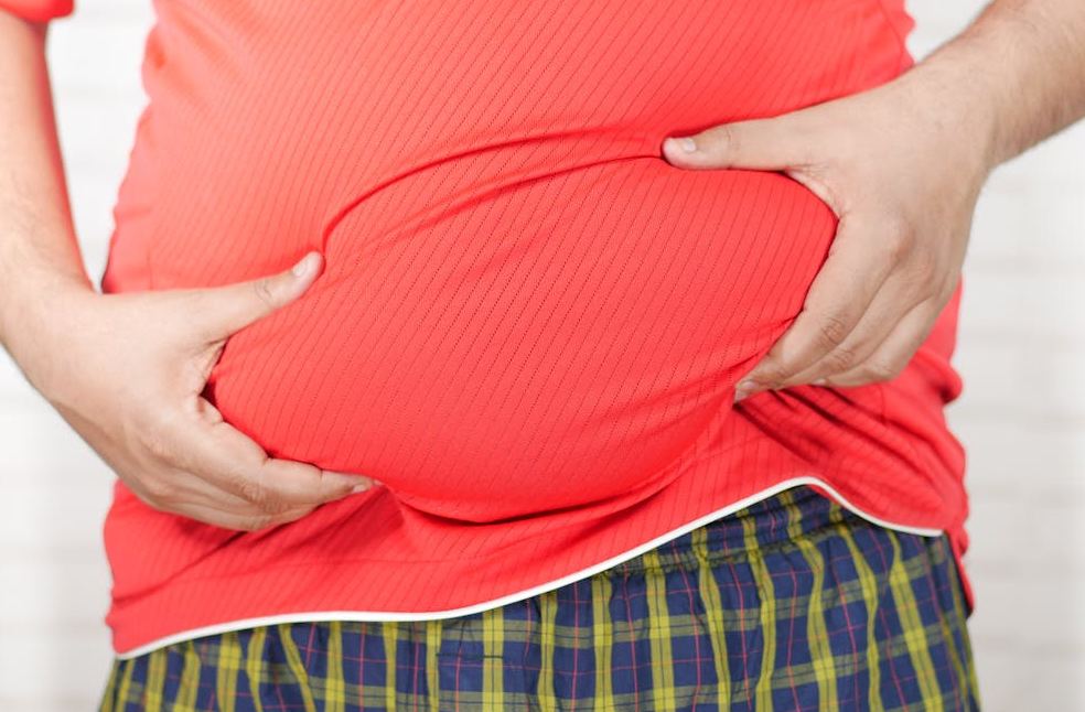 Close-up image of a man holding his bloated belly