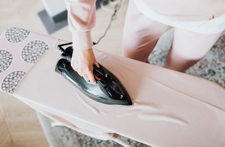 UK to cut VAT on household electricity bills from October A person using a steam iron on a pink ironing board indoors