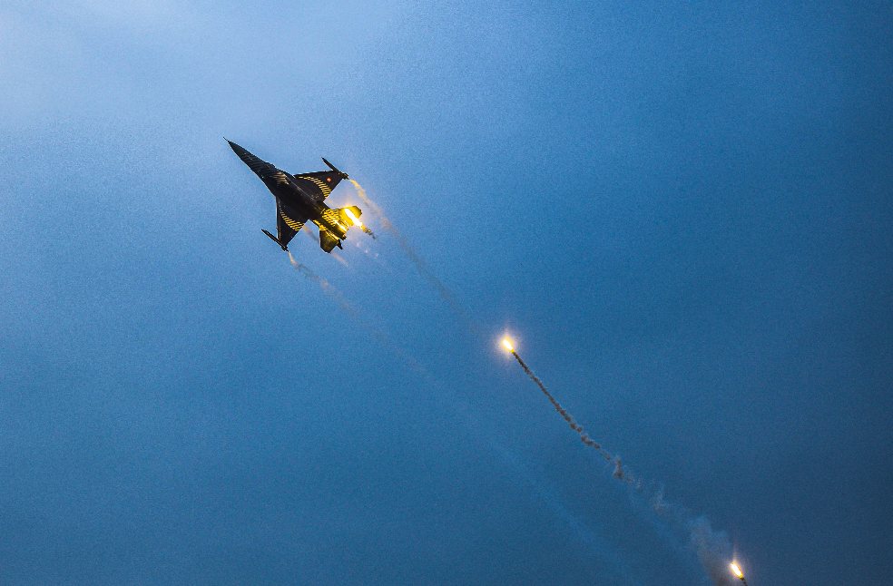 A thrilling aerial shot of a fighter jet releasing flares in a clear sky over Antalya