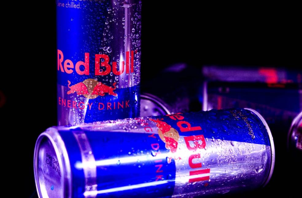Close-up of chilled Red Bull cans with water droplets, reflecting vibrant neon lighting