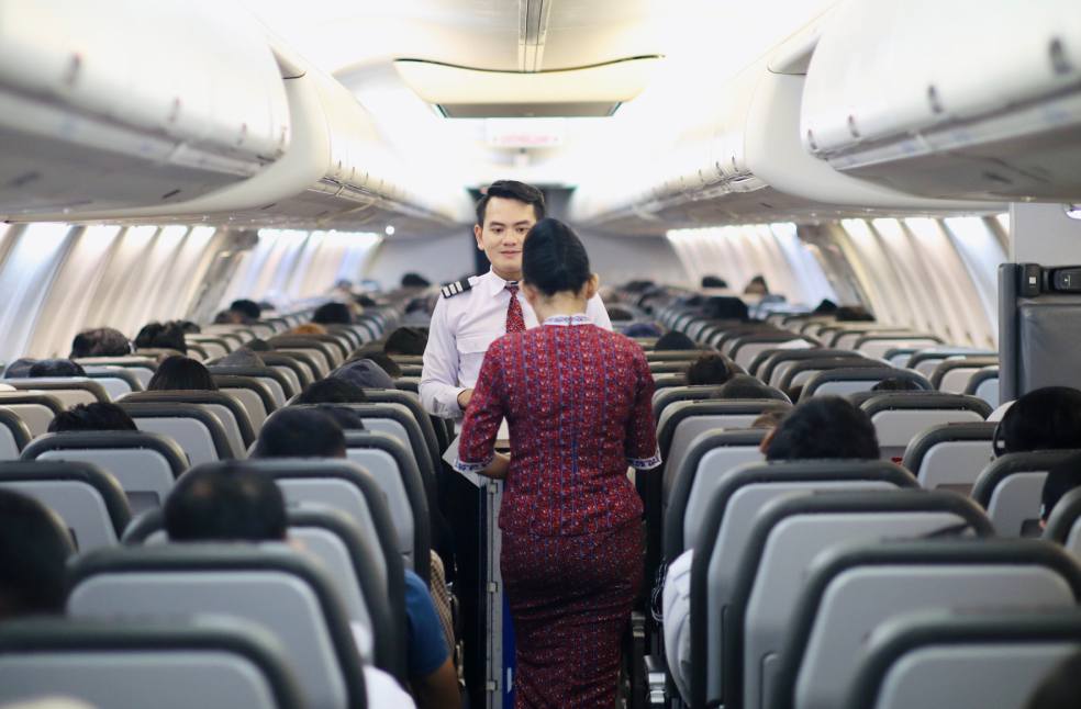 Flight attendants serving passengers inside an airplane cabin during a flight