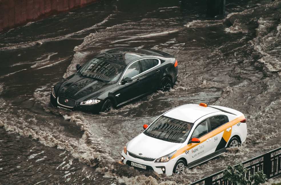 Cars navigating through a flooded city street, showcasing urban chaos and weather impacts.