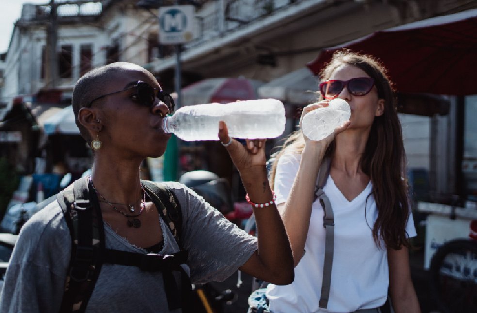 Two women quenching their thirst with bottled water during a sunny outdoor adventure