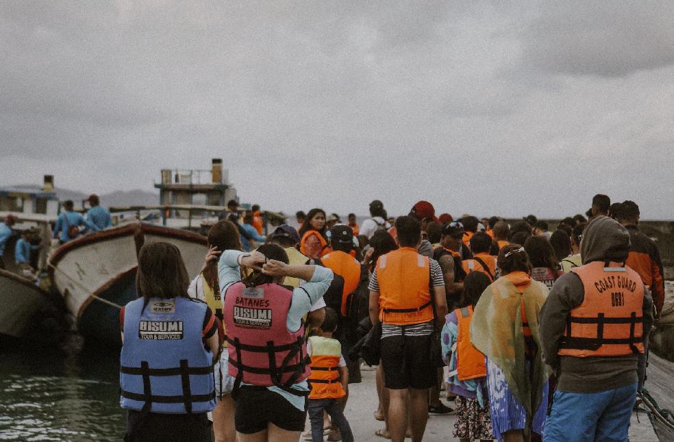 A group of tourists wearing life vests board boats at the shore of Basco, Batanes