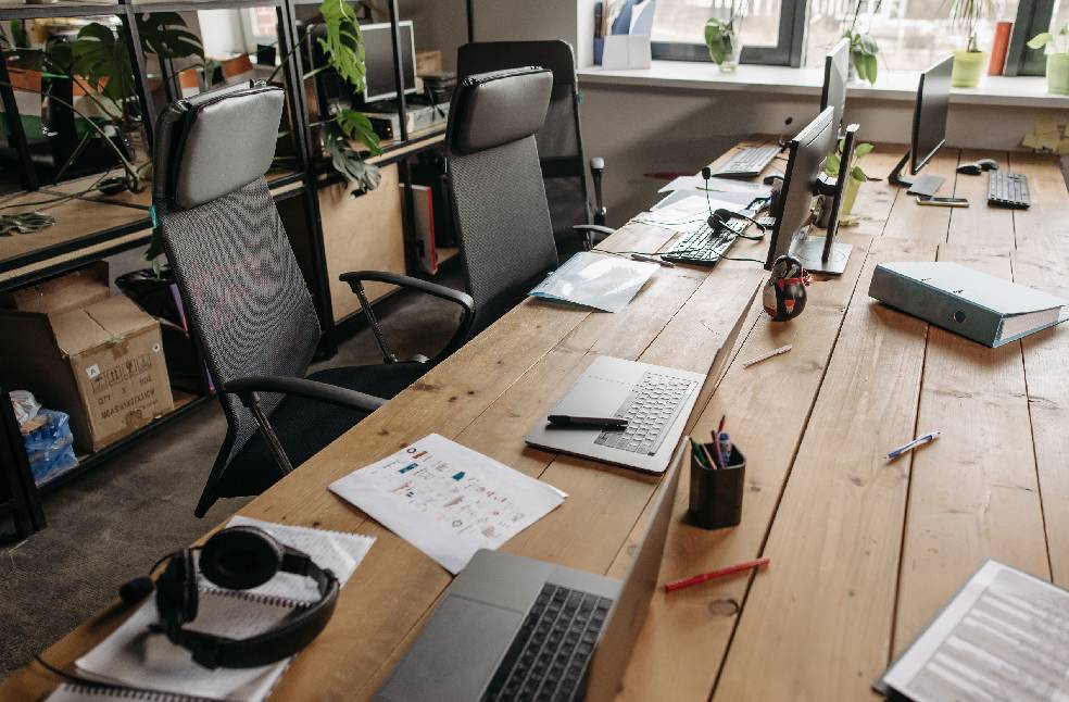 Spacious co-working office with wooden desks, laptops, and modern chairs.