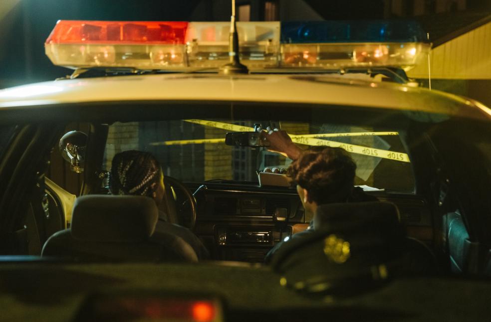 Police officers monitoring a scene through rearview mirror