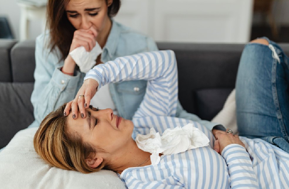 Two women experiencing emotional distress, sharing comfort on a couch indoors