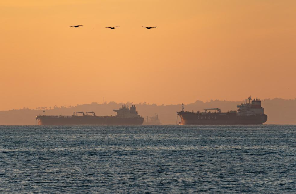 Silhouetted oil tankers on the Pacific Ocean at sunset near Long Beach