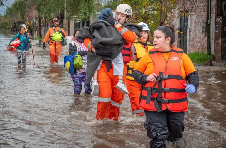 Taiwan initiates evacuations as Typhoon Bavi hits Japan Rescue workers in orange gear helping people during a flood, showcasing bravery and teamwork