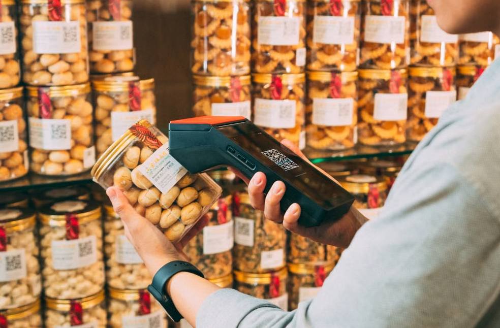 Individual scanning QR codes on jars in a store with a handheld device