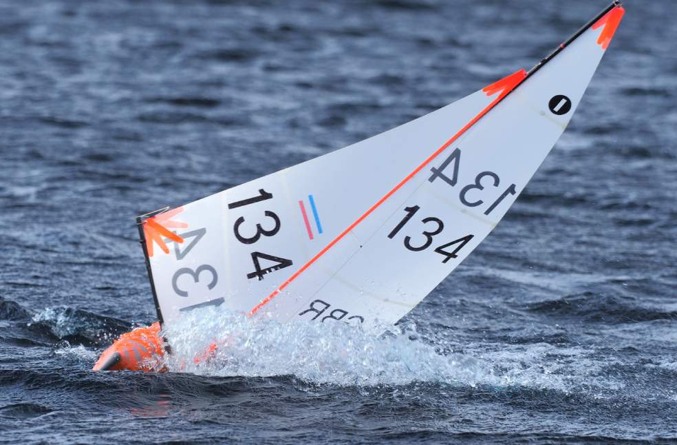 A detailed shot of a model sailboat capsized in water